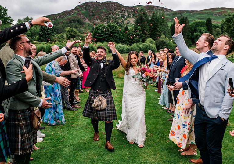 Bride and groom celebrate as they walk back down aisle through confetti thrown by their loved ones